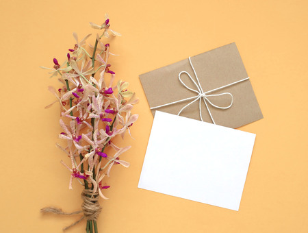 Blank white greeting card with orchis flowers bouquet on yellow background, minimal style.の写真素材