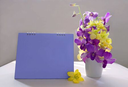 Blank desk calendar with yellow and purple orchid flowers.の写真素材