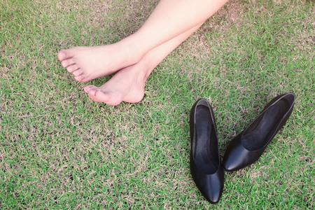 Woman legs relaxing on green grass barefoot without shoes.の写真素材