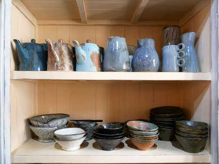 Handmade ceramic pottery standing on wooden shelves. Traditional craft japanese style.の写真素材