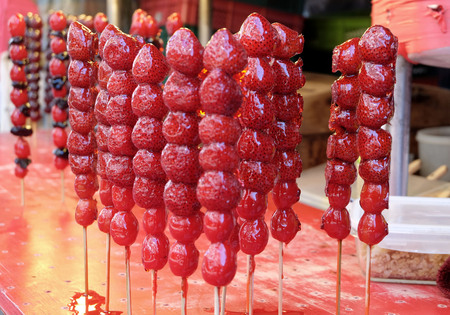 Crispy candied strawberries on a stick at street food market in Taiwan.の写真素材