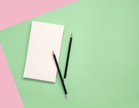 Empty notepad with pencils on green and pink background with copy space.の写真素材