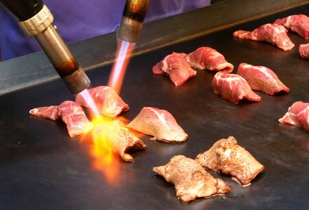 Cheff burns a slice of wagyu beef with blowtorch for make a sushi caramelize.の写真素材