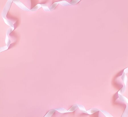Festive curled white ribbon border on pink background.の写真素材