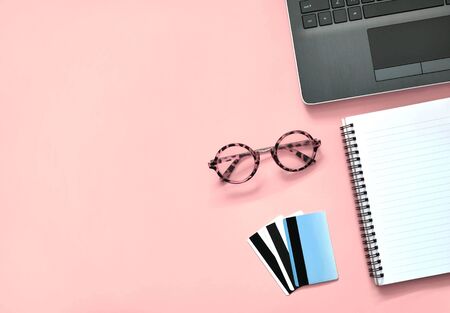 Workspace with laptop, notebook, credit cards note and eye glasses on pink background. Online shopping business concept.
の写真素材