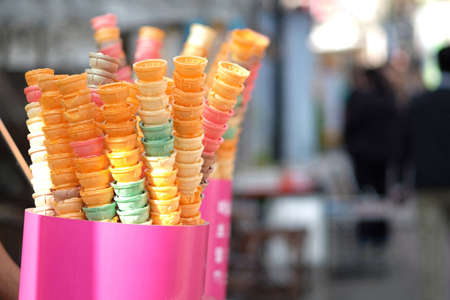 Colorful ice cream cones placed on stalls at outdoor street food market.