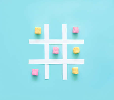 Tic tac toe made of pink and yellow marshmallows on a blue background.の写真素材