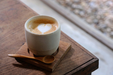 Coffee cup with heart shape latte art on wood tableの写真素材