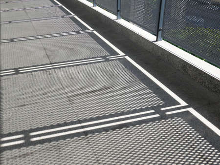 View of metal wire fence with daylight shadows
