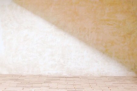 Beige cement wall texture background in empty room with light and shadow for product presentationの写真素材
