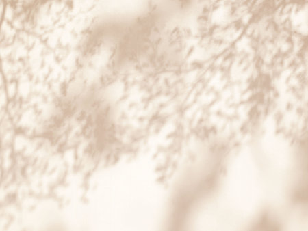 Natural shadow of leaves in warm autumn colors on concrete wall texture background