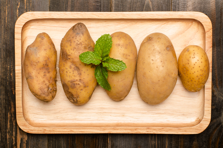 Potatoes with peppermint on wooden plateの写真素材