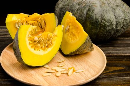 Slices of raw pumpkin on plate and wooden background