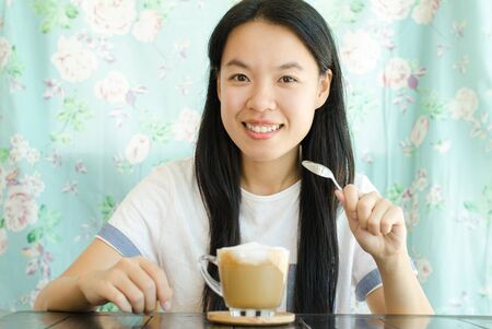 Young asian woman drinking coffee in the morningの写真素材