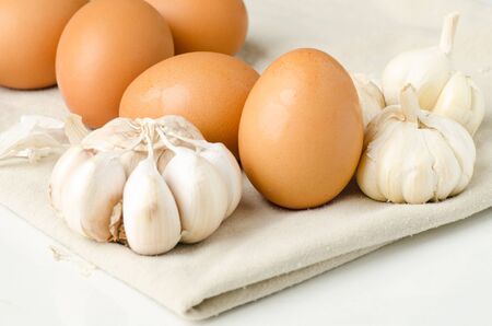 Eggs and garlic on fabric background (food ingredient)の写真素材