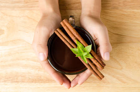 Cup of hot chocolate or cocoa hold by hand on wooden backgroundの写真素材