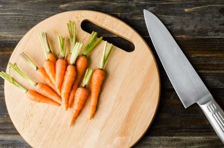 Fresh carrots on wooden plate ready for cookingの写真素材