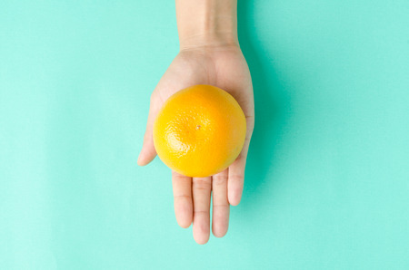 Fresh Navel orange fruit hold by hand on green backgroundの写真素材