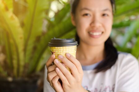 The cup of hot coffee hold by woman hand in the morningの写真素材