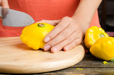Cutting of yellow patty pan squash on wooden plate for cookingの写真素材