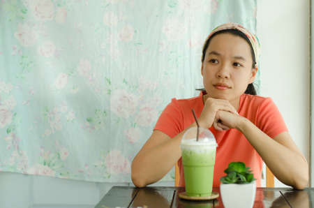 Asian woman drinking ice green tea and waiting someoneの写真素材