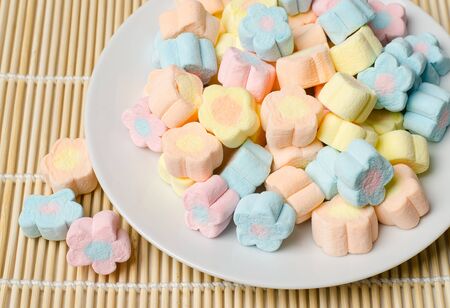 Colorful marshmallows (flower shape) on white plateの写真素材