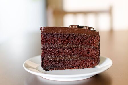 Piece of dark chocolate cake on white dish ready to eating