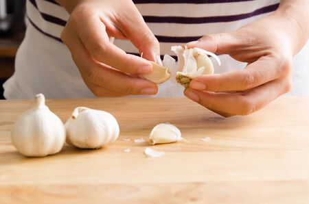 Woman peeling garlic by hand for cookingの写真素材