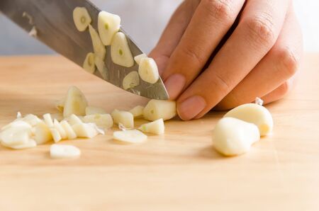Woman chopping garlic on wooden board for cookingの写真素材