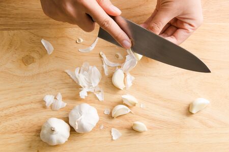 Woman peeling garlic by knife for cookingの写真素材