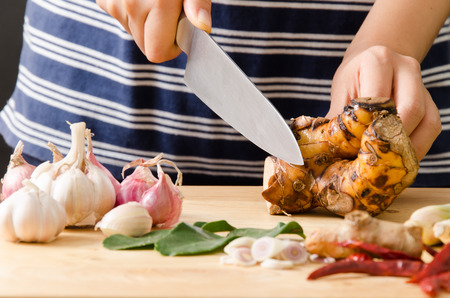 Woman cutting galangal on wooden board prepare for cooking Thai foodの写真素材