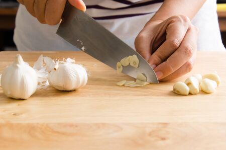 Woman chopping garlic on wooden board for cookingの写真素材