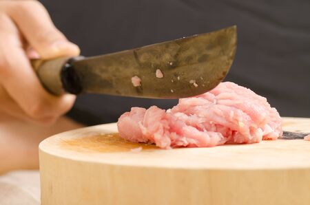 Chef chopping raw pork on wooden board for cookingの写真素材