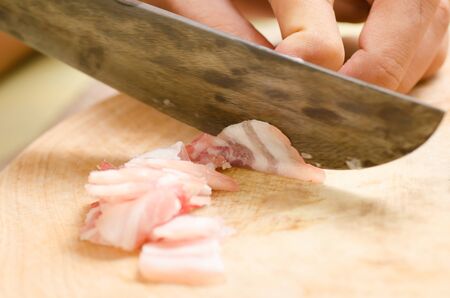 Chef slice streaky pork on wooden board for cooking