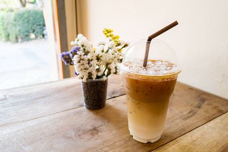 Glass of ice latte coffee on wooden table ready to drinkの写真素材