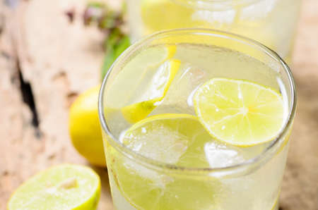 Cold lemonade with ice and fresh slice lemon in the glass on wooden plate,Healthy drink in summer