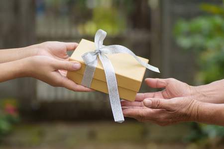 Golden gift box in hand for giving in holidaysの写真素材