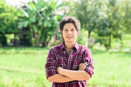 Asian young farmer standing in green fieldの写真素材