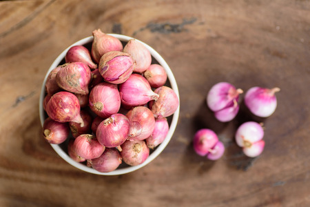 Top view of shallots in a bowl and wooden background, spice and herb, food ingredientの写真素材