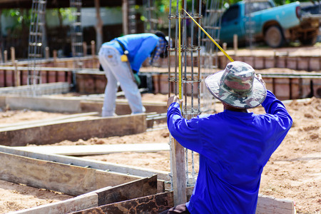 The worker holding measuring tape on formwork at construction site