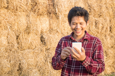 Young smart farmer using smartphone for management in a farm in Thailandの写真素材