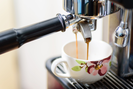 Coffee making, hot coffee flowing into a cup from espresso machineの写真素材