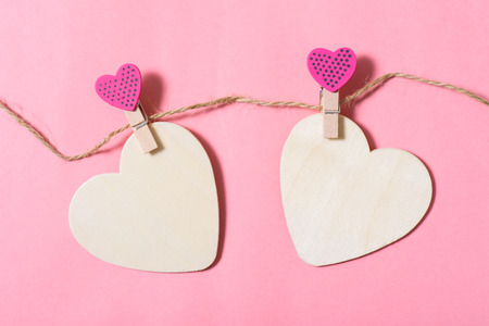 Two white hearts with cute pink clothes pegs on pink background, Valentine conceptの写真素材