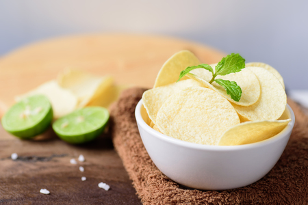 Potato chips in a bowl on brown fabricの写真素材