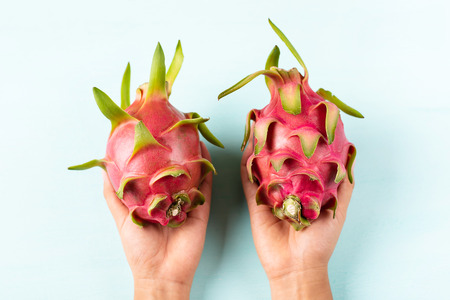 Ripe dragon fruit holding by hand on color background, top view, tropical fruitの写真素材