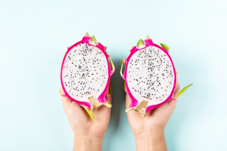 Half of dragon fruit holding by hand on color background, top viewの写真素材