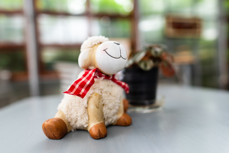 Smile sheep doll on the table in the coffee shopの写真素材