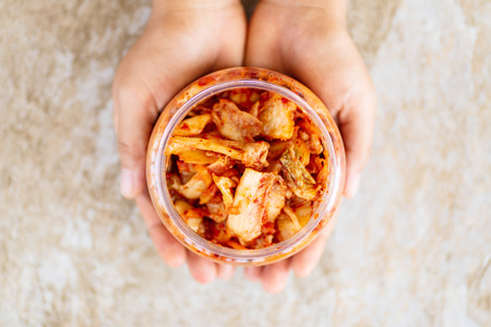 Kimchi cabbage in a bowl holding by hand, Korean food, top viewの写真素材