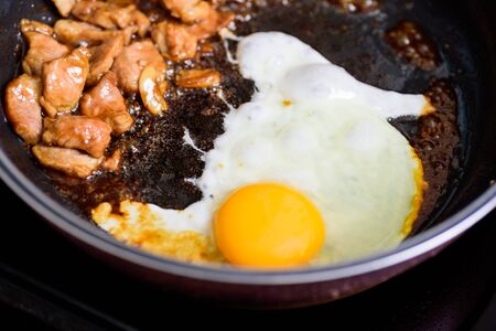 Stir fried egg and pork with soy sauce in a hot pan, Asian food cookingの写真素材