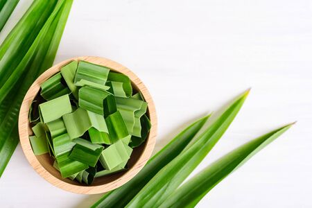 Sliced pandan leaf in a bowl and fresh pandan leaf on white background, pandan leaf used to enhance the flavoring and color in Asia food and dessertの写真素材